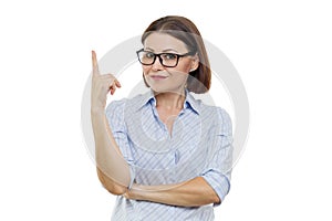 Portrait of middle-aged woman in glasses with index finger up, attention, white background isolated