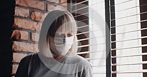 Portrait middle-aged woman in medical protective mask, self-isolation at home. Lockdown, quarantine during pandemic