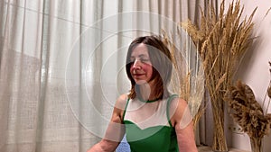 Portrait middle-aged woman meditating in half lotus position indoors