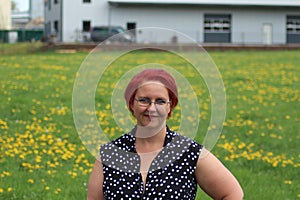 Portrait of a middle-aged woman with red hair on a background of green grass