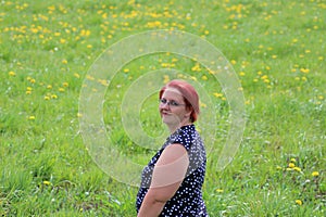 Portrait of a middle-aged woman with red hair on a background of green grass