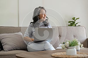 Portrait of middle aged woman sitting at with laptop at home