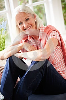 Portrait Of Middle Aged Woman Sitting On Window Seat