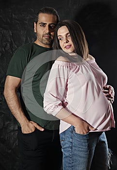 Portrait of middle eatern man hugging caucasian pregnant wife