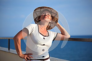 Portrait of middleaged woman in hat on balcony