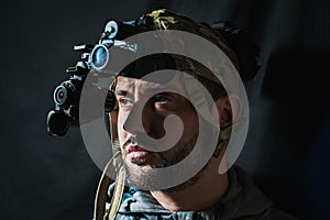 Portrait of a military man with a beard with a binocular night vision device on his head