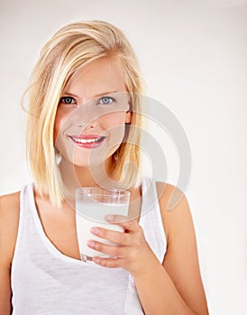 Portrait, milk and health with a woman drinking from a glass in studio isolated on a white background. Healthy
