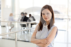 Portrait of millennial female employee posing with arms crossed