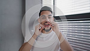 Portrait millennial handsome bearded arab indian male guy in white shirt brushing teeth using dental floss morning