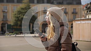 Portrait of millennial young woman girl is walking across the square in the old European city of the pier and she is