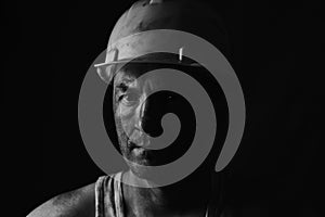 Portrait miner in helmet and undershirt with dirty face