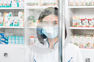 Portrait of a minority group doctor or pharmacist with mask on looking through a protective screen shield