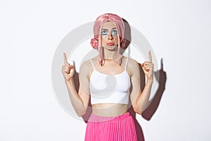 Portrait of miserable cute party girl in pink wig, sobbing and pouting upset, looking disappointed and pointing fingers