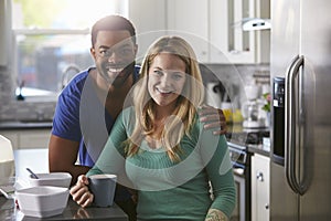 Portrait of mixed race couple in kitchen, man leaning down