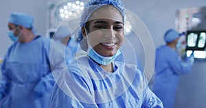 Portrait of mixed race female doctor standing in operating theatre smiling to camera