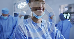 Portrait of mixed race female doctor standing in operating theatre smiling to camera