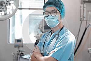 Portrait of mixed race male doctor standing in operating theatre wearing face mask