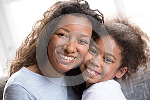 Portrait of mixed race mom and daughter hug at home