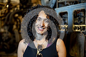 Portrait of a mixed race woman smiling while posing inside an abandoned factory.