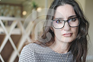 Portrait of mixed race young woman looking at camera. mid east woman wearing eyeglasses. calm brunette with long hair