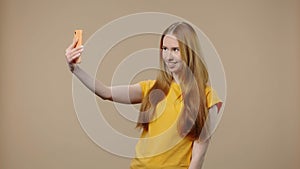 Portrait of model with natural beauty is talking on a video call using a smartphone. Young girl with long hair in yellow