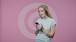 Portrait of a model with natural beauty is texting on her phone. Young girl with long hair in blue t-shirt poses on