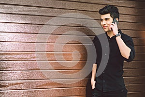 Portrait model young handsome male suspect Turkish middle eastern brunette in black shirt uses hand phone to call