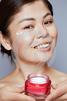 Portrait of modern asian woman with facial cream jar