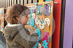 Portrait of a modern little boy playing with a busy board outdoors