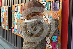 Portrait of a modern little boy playing with a busy board outdoors