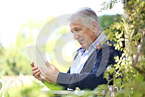 Portrait of modern senior man reading book on tablet
