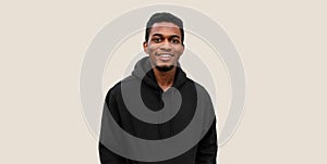 Portrait of modern smiling young african man looking at camera wearing black hoodie isolated on gray background