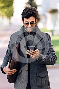 Modern young man using his mobile phone in the street.