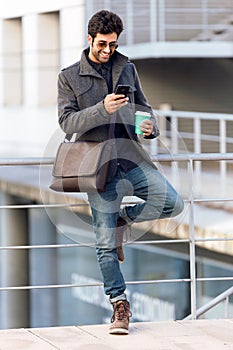 Modern young man using his mobile phone in the street.