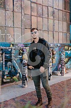 Portrait of Modern Young Person Hipster Guy Standing Alone in Urban Street Covered Colorful Graffiti Alleyway Outside in the City