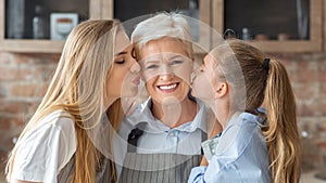 Portrait of mom and daughter kissing granny