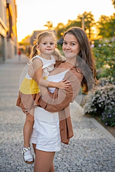 Portrait of mom and her little daughter playing on city street it sunset lights