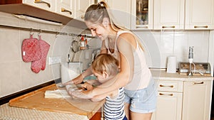 Portrait of mother with 3 years toddler son baking cookies on kitchen at morning. Family baking and cooking at home