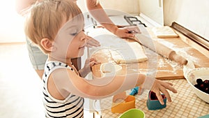 Portrait of mother with 3 years toddler son baking cookies on kitchen at morning. Family baking and cooking at home