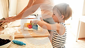 Portrait of mother with 3 years toddler son baking cookies on kitchen at morning. Family baking and cooking at home