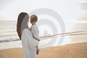 Portrait of mother and baby in the beach at sunset