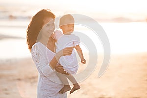 Portrait of mother and baby in the beach at sunset