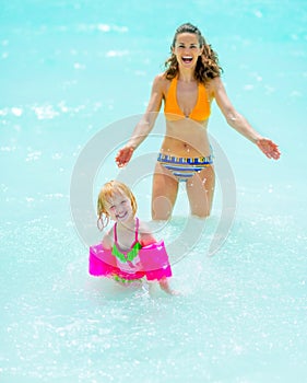 Portrait of mother and baby girl playing in sea