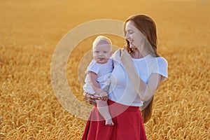 Portrait of mother and child on the background of wheat field. Mom and baby smiling