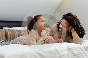 Portrait of mother and daughter lying on bed in bedroom at home
