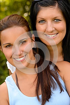 Portrait of mother and daughter smiling outdoors