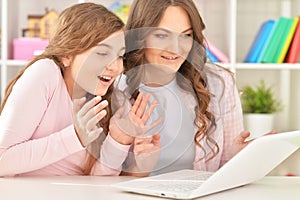 Portrait of mother and daughter using laptop