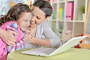 Portrait of mother and daughter using laptop