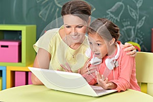 Portrait of mother and daughter using laptop