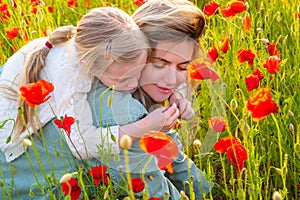 Portrait of mother and daughter walking through a flowering poppy field. Summer family holidays on nature. Summer on